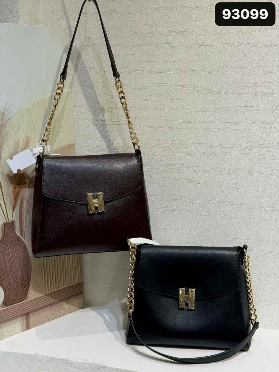 Logo Flap Shoulder Bag is a structured rectangular handbag featuring a smooth leatherette finish, a front envelope flap secured with a gold-tone "H" buckle hardware, and gold chain-link shoulder strap accents.